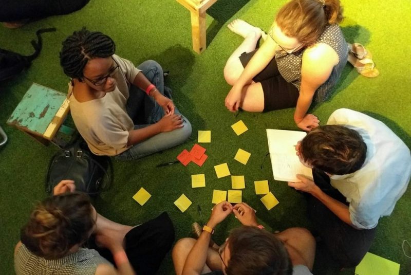 Des participants écrivent des mots-clés sur des post-it lors de la soirée ExistenZ